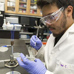 A picture of an SFSU scientist in a lab coat experimenting with an open flame